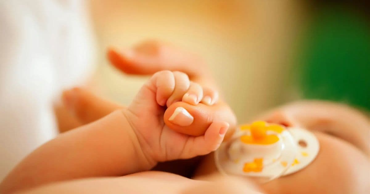 Close-up of an infant holding an adult finger, representing pediatric emergency nursing care and assessment