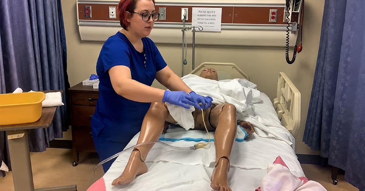 CNA nurse aide training student practising hands-on patient care skills with a training mannequin in a clinical lab